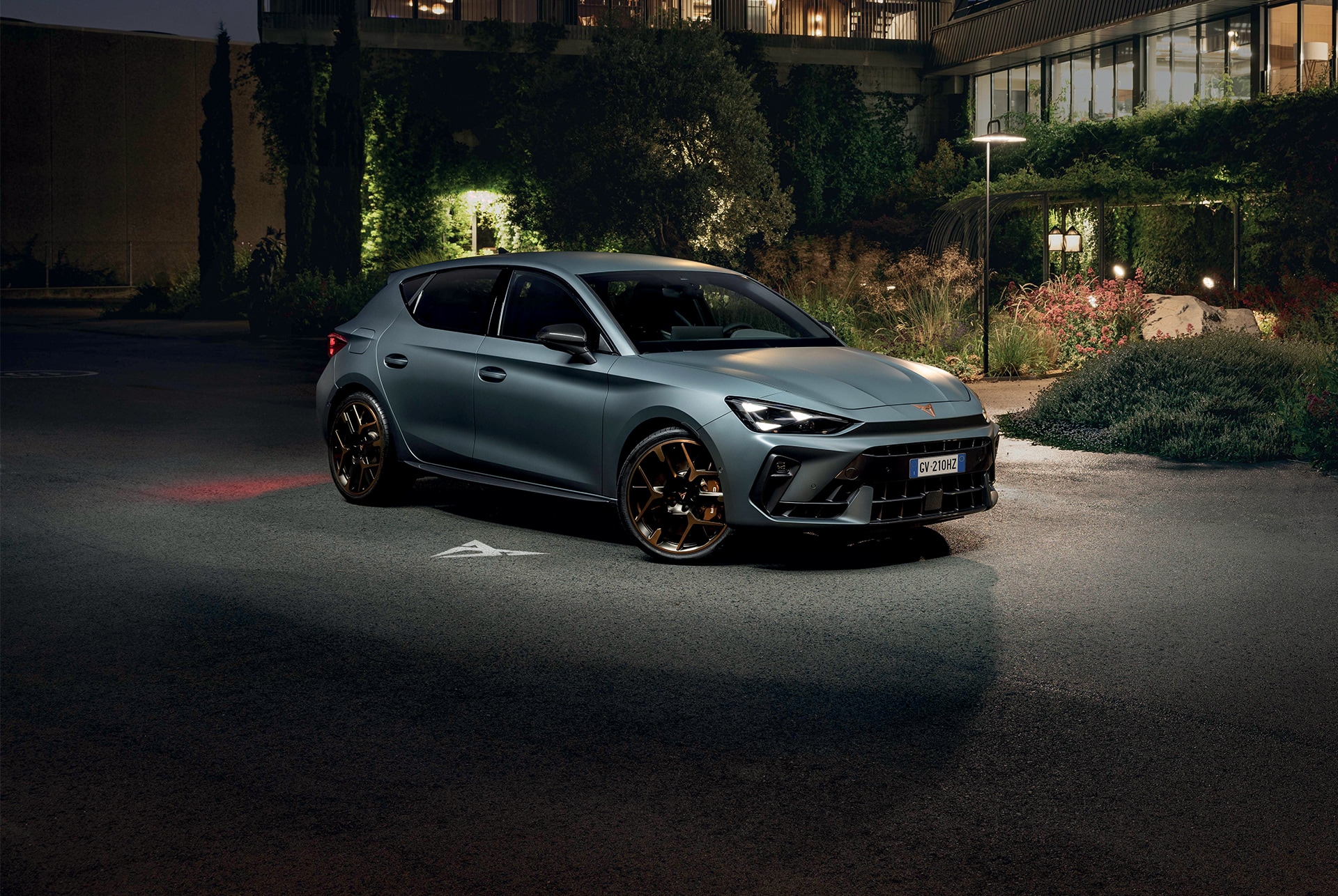 Versioni ed equipaggiamenti della nuova CUPRA Leon 2024, prese d'aria, fari a forma triangolare, tramonto, pannelli in vetro, architettura e cielo blu.