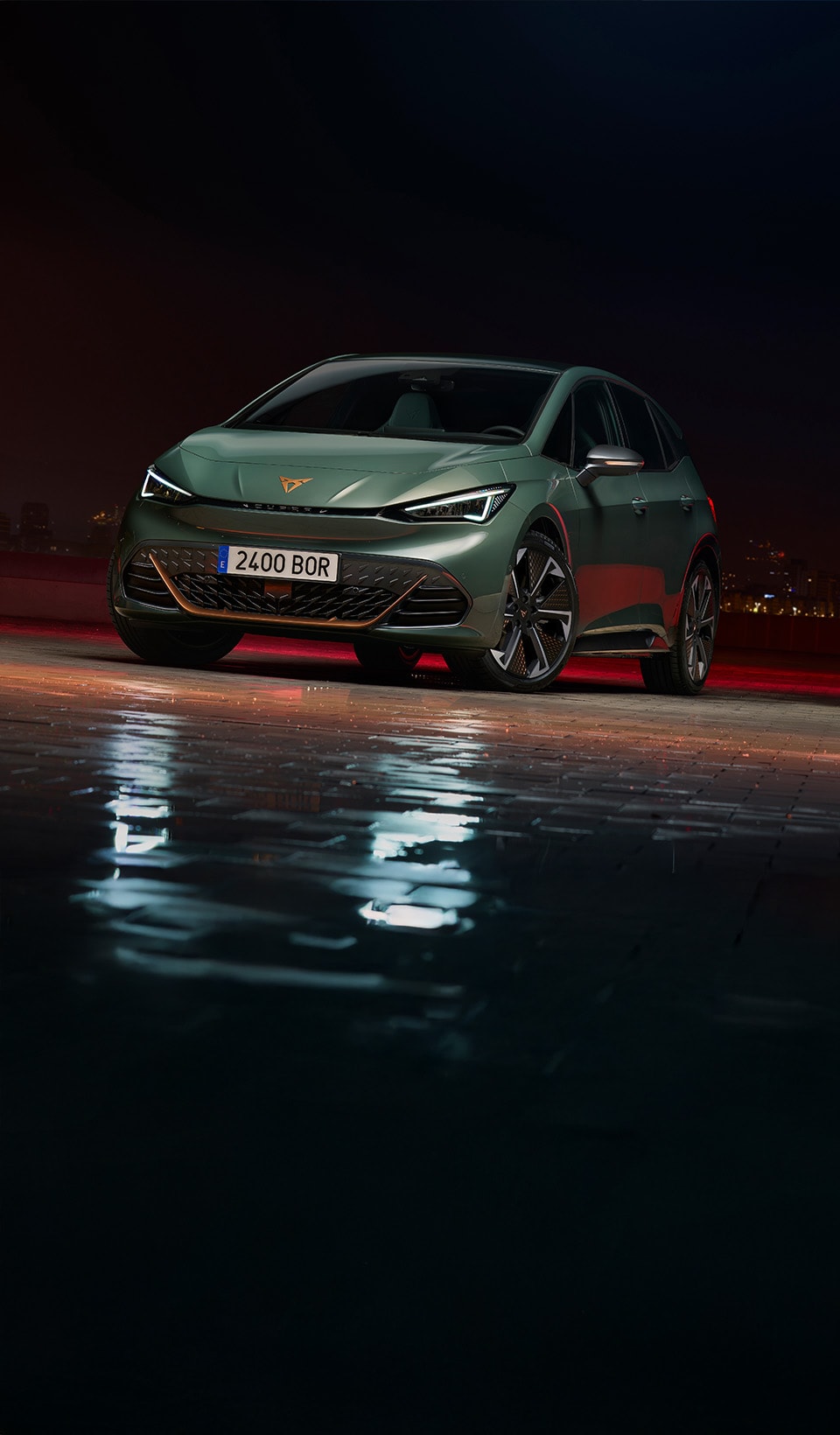A CUPRA Formentor CUV suspended diagonally, next to a rocky, cliff-like structure. A charging cable is connected to the car from a charging unit on the cliff face.