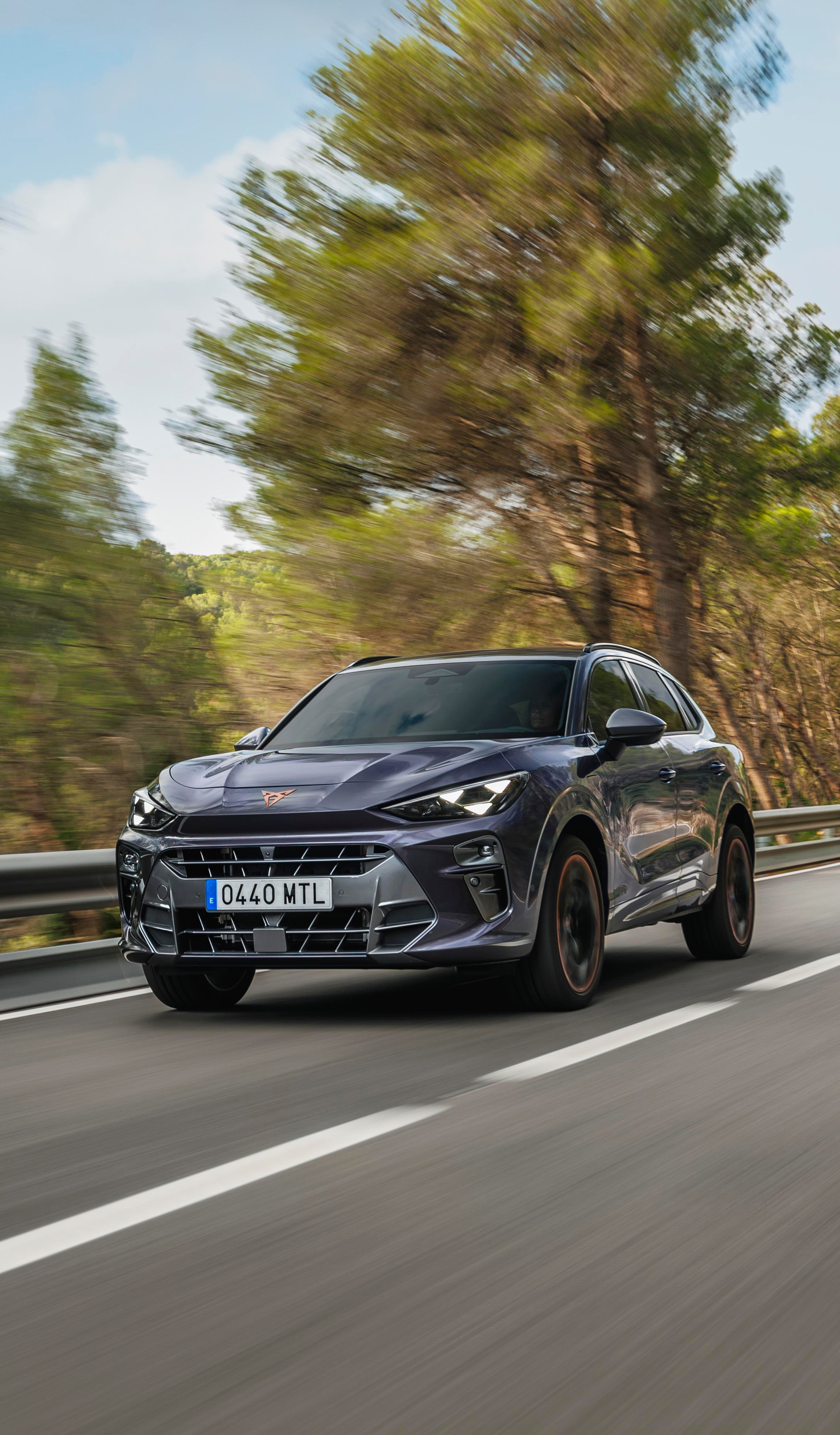 A CUPRA Leon Sportstourer shown from an elevated angle, with a person draped in dark, flowing fabric that creates a dynamic, red-lit trail beside the car.
