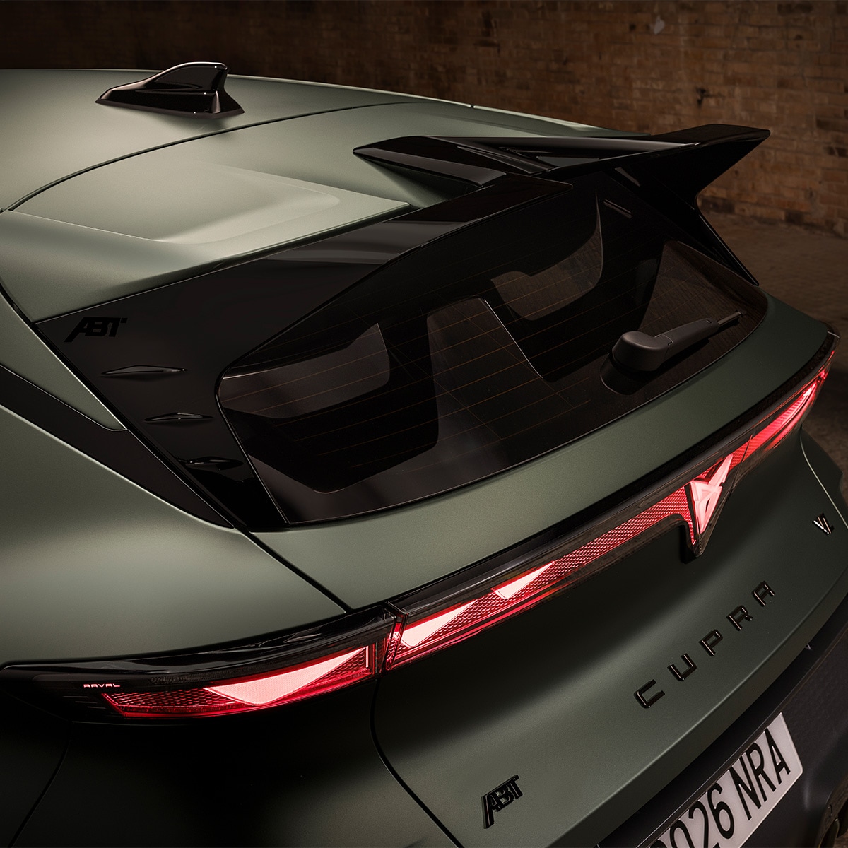 Rear-side view from a high    angle of the CUPRA Raval, revealing    Custom Pack details such as the    aggressive rear wing spoiler and rear    air curtains.  