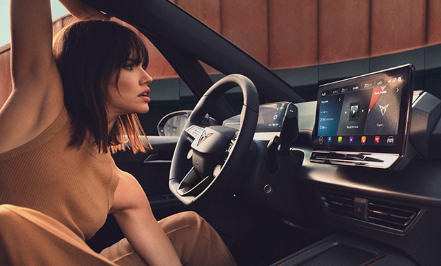 Donna che visualizza gli aggiornamenti OTA della CUPRA sul dispositivo di infotainment della sua vettura